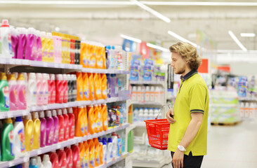 Man shopping in supermarket reading product information.(diapers,detergent)