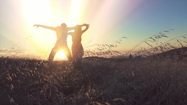 Aerial: Male and female ballet dancer embracing with light rays coming through them at sunset