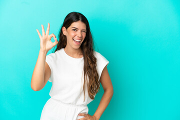 Fototapeta na wymiar Young caucasian woman isolated on blue background showing ok sign with fingers