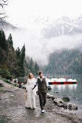 The concept of a wedding. A happy married couple in love in wedding clothes hugs standing in the middle of a boat pier a lake and misty mountains in nature in a fabulously beautiful place outdoors