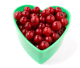 Red currant heart isolated on a white background.A heart-shaped cookie mold filled with red currants.Garden fresh berries, bright and shiny.