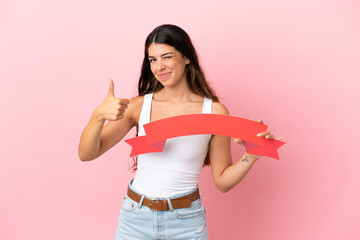Young caucasian woman isolated on pink background holding an empty placard with thumb up