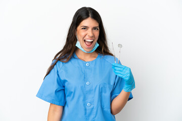 Dentist woman holding tools over isolated white background with surprise facial expression