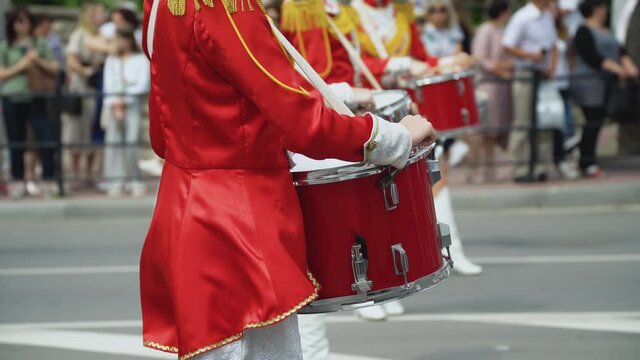 Young girls drummer in red vintage uniform at the parade. Street performance of festive march of drummers girls in red costumes on city street