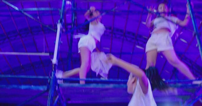 Many female dancers dressed in white shorts dancing inside abandoned building in high multistage  construction . Stylish Girls dancing, twerking , doing gymnastic movements , jumping . 