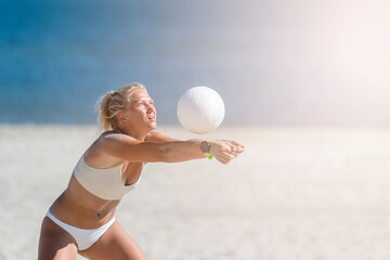 Young girl playing volleyball on the beach. Professional sport concept