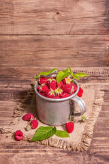 Raspberries background. Ripe fruits in a vintage mug, rustic style