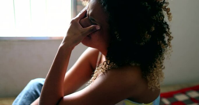 Tearful Brazilian woman crying, black latina girl in tears sitting in bed