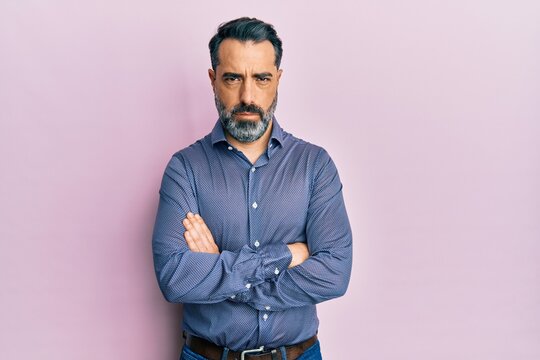 Middle age man with beard and grey hair wearing business clothes skeptic and nervous, disapproving expression on face with crossed arms. negative person.