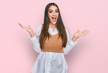 Young beautiful woman wearing casual white shirt celebrating victory with happy smile and winner expression with raised hands