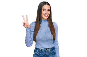 Young beautiful woman wearing casual winter sweater smiling with happy face winking at the camera doing victory sign. number two.