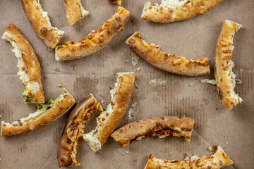 Pizza crusts in a greasy box on a home table. Leftover pieces of pizza. Bread crumbs, grease stains...
