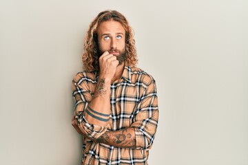 Handsome man with beard and long hair wearing casual clothes serious face thinking about question...