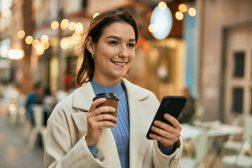 Young hispanic woman using smartphone and drinking coffee at the city.