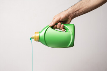 Male hand pouring detergent liquid from a green bottle with blank label - editable mockup template