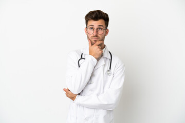 Young doctor caucasian man over isolated on white background wearing a doctor gown and thinking