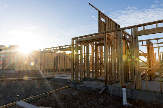 Sun flare shines through wooden house frame on  concrete pad