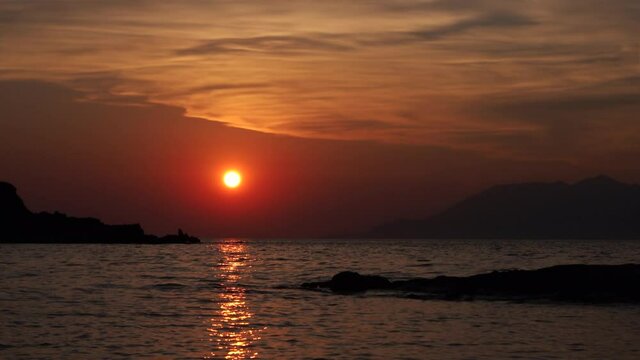 Gokceada, Imbros Island sunset view with mountains sea waves and the opposite island of Samothrace. Arcadia Kardamos district. 4K motion. Time-lapse sunset sea and mountain view on the beach.  