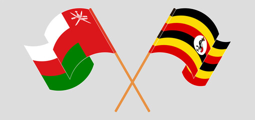 Crossed and waving flags of Oman and Uganda