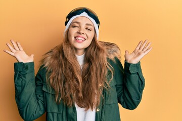 Beautiful blonde caucasian woman wearing snow wear and sky glasses celebrating mad and crazy for success with arms raised and closed eyes screaming excited. winner concept