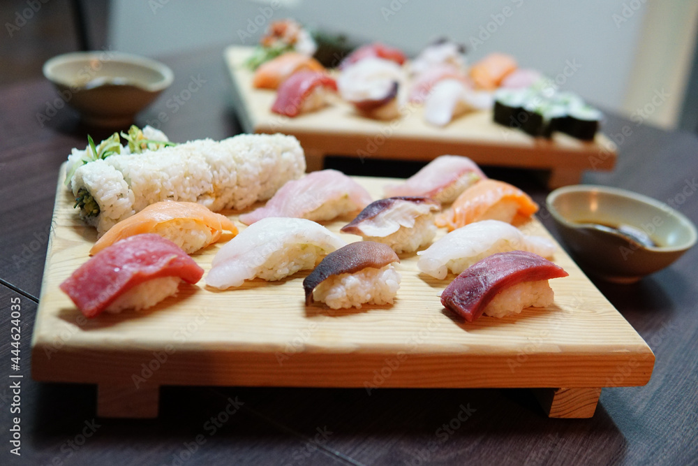 Sticker portions of delicious sushi served on a traditional wooden board with soy sauc