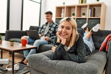 Young caucasian couple smiling happy using laptop sitting on the sofa at home.