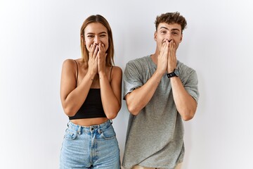 Young beautiful couple standing together over isolated background laughing and embarrassed giggle...