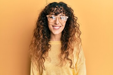 Young hispanic girl wearing casual clothes and glasses looking positive and happy standing and smiling with a confident smile showing teeth