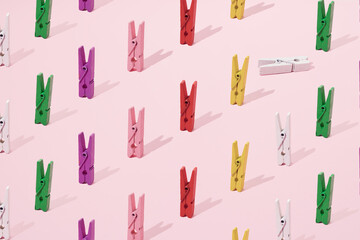 Small wooden colorful pegs.for loundry and paper on a pink background. Minimal design and pattern.