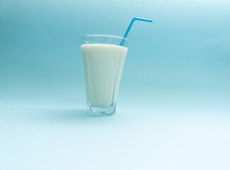 Glass of fresh, organic, cold milk with blue drinking straw. Creative minimal concept.