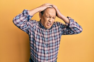 Handsome senior man with grey hair wearing casual shirt suffering from headache desperate and stressed because pain and migraine. hands on head.