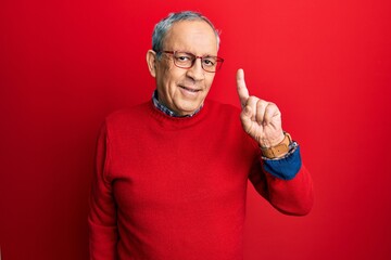 Handsome senior man with grey hair wearing casual clothes and glasses showing and pointing up with...