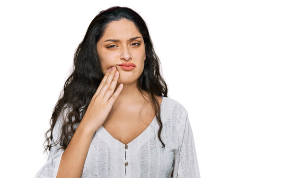 Brunette young woman wearing casual clothes touching mouth with hand with painful expression because of toothache or dental illness on teeth. dentist
