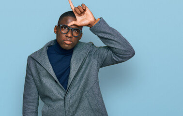 Young african american man wearing business clothes and glasses making fun of people with fingers...
