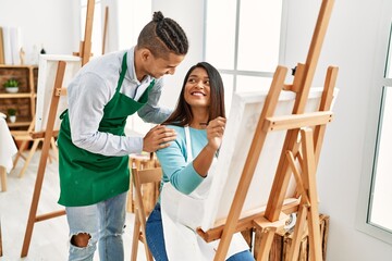 Young latin painter couple smiling happy painting at art studio