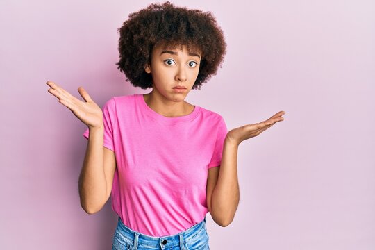 Young hispanic girl wearing casual clothes clueless and confused with open arms, no idea and doubtful face.