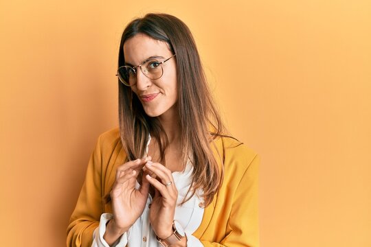Young beautiful woman wearing business style and glasses hands together and fingers crossed smiling relaxed and cheerful. success and optimistic