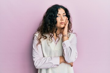 Young brunette woman with curly hair wearing casual clothes thinking looking tired and bored with depression problems with crossed arms.