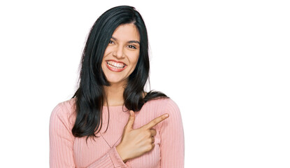 Young hispanic woman wearing casual clothes cheerful with a smile of face pointing with hand and finger up to the side with happy and natural expression on face