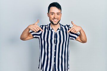 Fototapeta premium Young hispanic man wearing casual clothes looking confident with smile on face, pointing oneself with fingers proud and happy.
