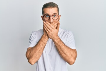 Young caucasian man wearing casual clothes and glasses shocked covering mouth with hands for...
