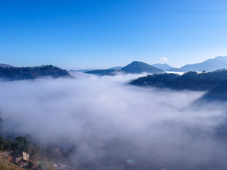 Aerial view of Itaipava, Petrópolis. Early morning with a lot of fog in the city. Mountains with blue sky and clouds around Petrópolis, mountainous region of Rio de Janeiro, Brazil. Drone photo. 
