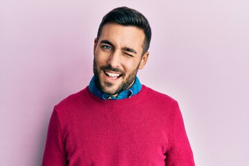 Young hispanic man wearing casual clothes winking looking at the camera with sexy expression, cheerful and happy face.