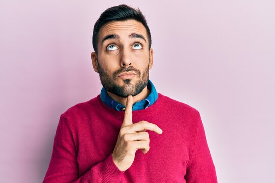 Young hispanic man wearing casual clothes thinking concentrated about doubt with finger on chin and looking up wondering