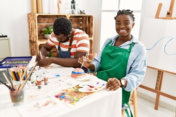 African american painter couple smiling happy painting pottery sitting on the table at art studio.