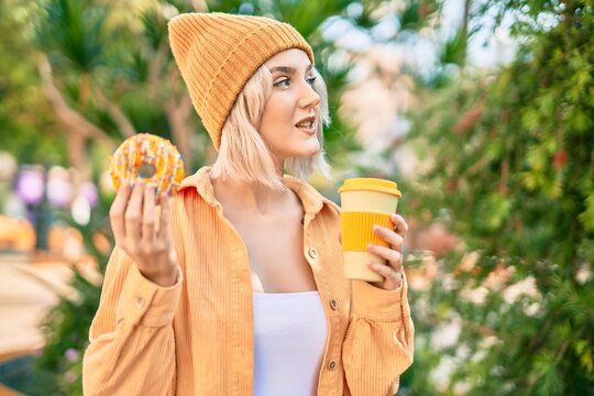 Young blonde girl smiling happy having breakfast at the park.