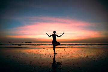 Fototapeta na wymiar Silhouette of yoga woman on the ocean beach at surreal sunset.