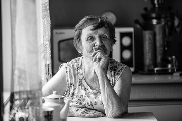 Portrait of an old woman in her home. Black and white photo.
