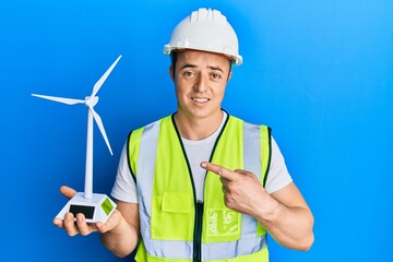 Handsome young man holding solar windmill for renewable electricity smiling happy pointing with hand and finger