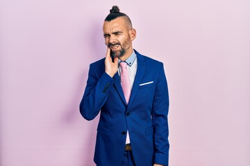 Young hispanic man wearing business suit and tie touching mouth with hand with painful expression because of toothache or dental illness on teeth. dentist